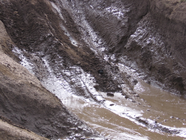 Muddy terrain with tire tracks and standing water