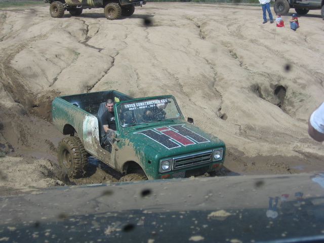 Green off-road vehicle with 'H' logo stuck in mud, 'UNDER CONSTRUCTION 4X4' text visible