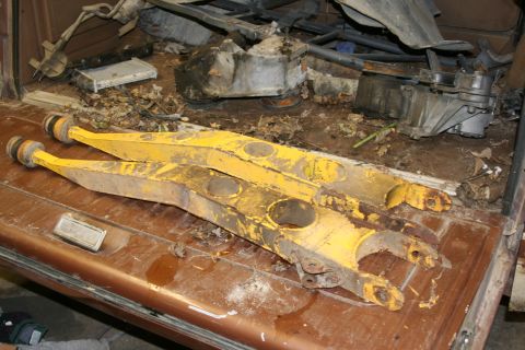 1989 Ford Bronco - Yellow suspension arms, likely for a lift kit, are stored in the bed of a vehicle.