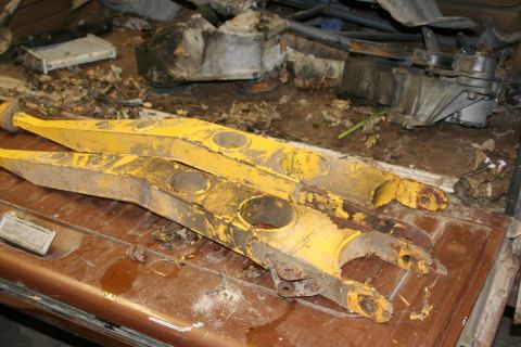 1989 Ford Bronco - Yellow suspension control arms are visible on a brown surface, with a "SUPERMOTORS" logo in the lower right corner.