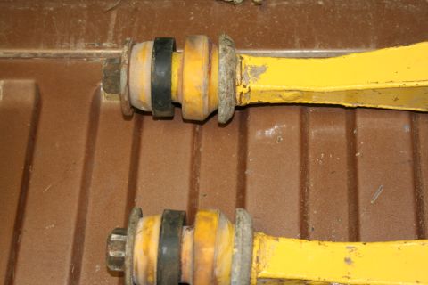 1989 Ford Bronco - Yellow suspension control arms with rubber bushings and bolts are shown.