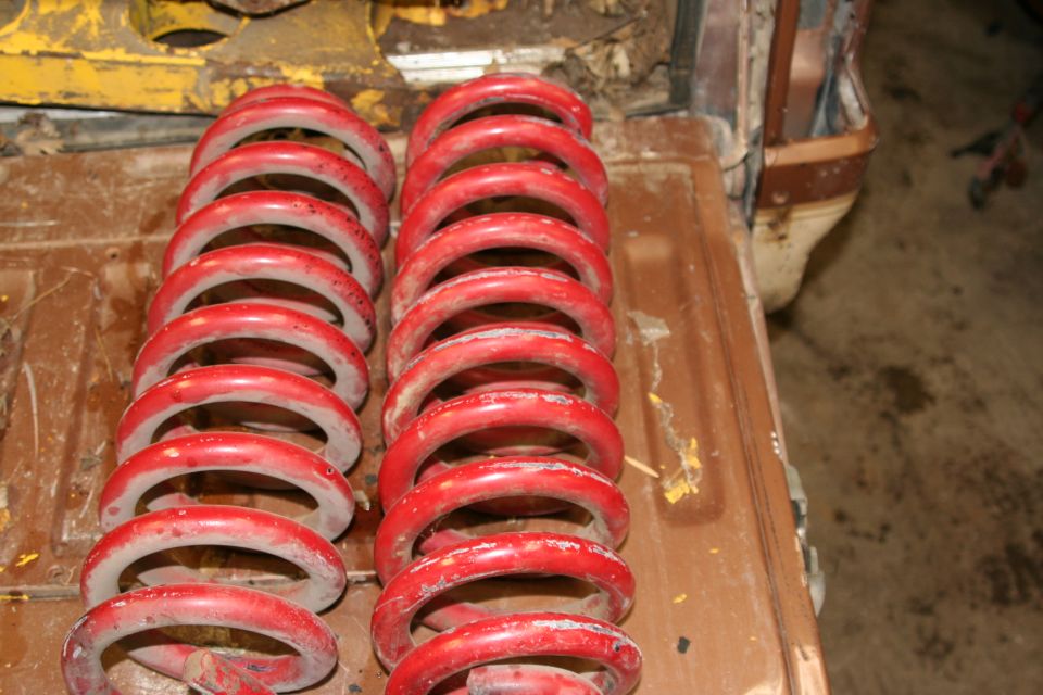 two rows of red coil springs on a wooden surface