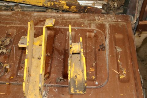 1989 Ford Bronco - Yellow metal brackets on a rusty surface, possibly from a lift kit.