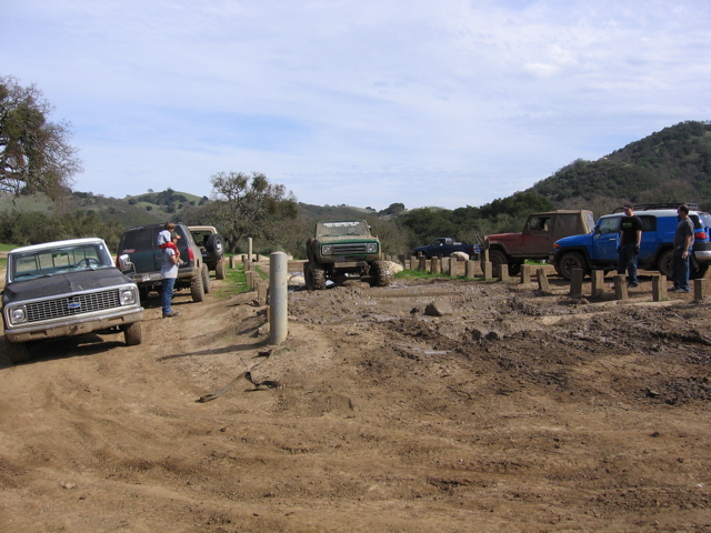 Muddy off-road scene with several trucks and SUVs