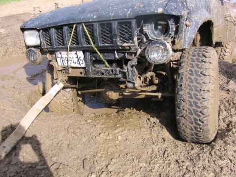 1989 Ford Bronco - This vehicle is deeply embedded in mud, with its front tires and undercarriage submerged.