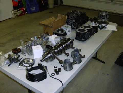 1982 Chevrolet C/K Pickup - Various engine parts are organized on a table, including a crankshaft, pistons, and cylinders.