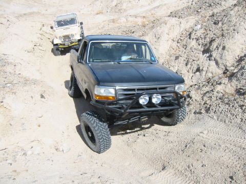 1992 Ford Bronco - Black 1992 Ford F-150 pickup truck navigates a dirt trail, followed by a white Jeep.
