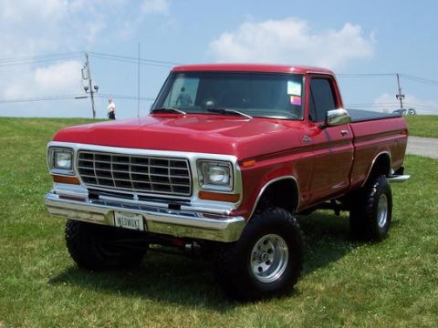1974 Ford F-100 - This lifted red pickup truck features a prominent chrome grille and a custom license plate.