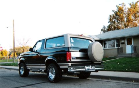 1996 Ford Bronco - This two-tone 1996 Ford Bronco is parked on a residential street, showing its rear profile and spare tire carrier.