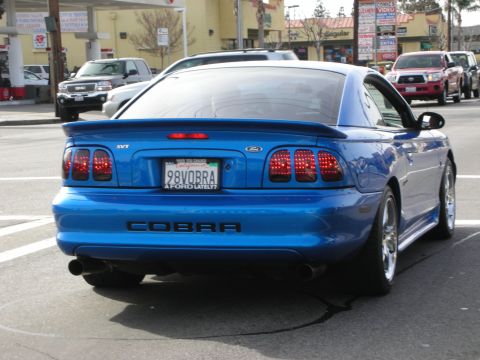 1998 Ford Crown Victoria - Rear view of a blue Ford Mustang SVT Cobra showing the COBRA decklid badge and a '98VOBRA' California plate.