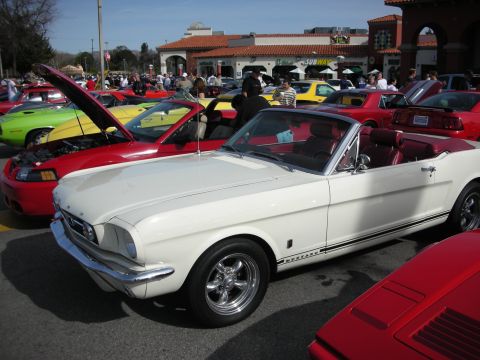 1998 Ford Crown Victoria - white first-generation Ford Mustang convertible with red interior parked among muscle cars at a lot car show.