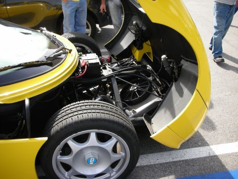 1998 Ford Crown Victoria - Exposed rear suspension, wheel and tubular chassis of a yellow mid-engine sports car with its rear clip lifted.