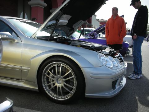 1998 Ford Crown Victoria - lowered silver Mercedes-Benz CLK with large multispoke wheels and its hood open as two men look on.