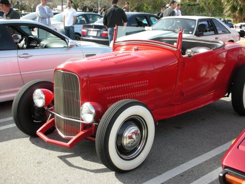 1998 Ford Crown Victoria - red 1920s-style Ford hot rod roadster with whitewall tires and chrome grille parked at a car show.