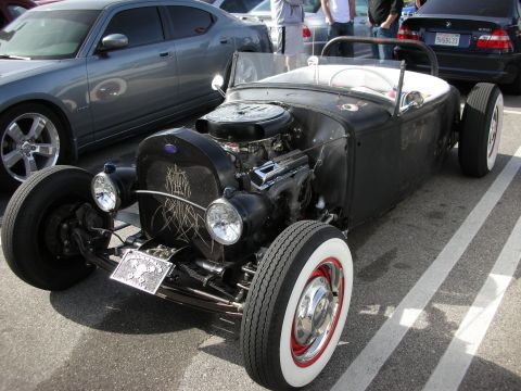 1998 Ford Crown Victoria - flat-black hot rod roadster with pinstriping, exposed V8 engine and whitewall tires at a car show.