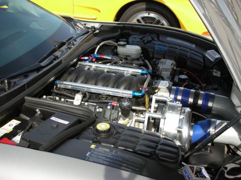 1998 Ford Crown Victoria - LS-style V8 engine with a belt-driven supercharger and blue plumbing in the bay of a yellow sports car.