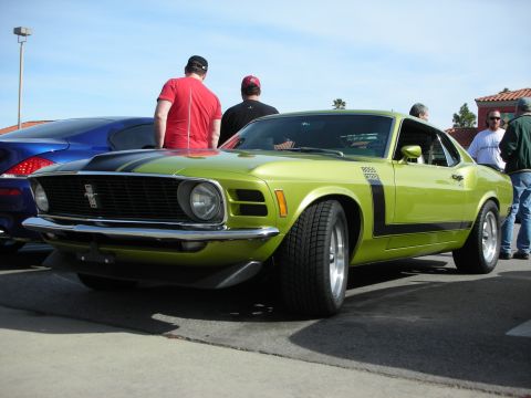 1998 Ford Crown Victoria - lime-green Ford Mustang Boss 302 fastback with black stripes parked at a sunny outdoor car show.