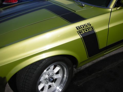 1998 Ford Crown Victoria - Close-up of a lime-green Boss 302 Mustang's front fender showing the black C-stripe, BOSS 302 graphic, and a polished 5-spoke wheel.