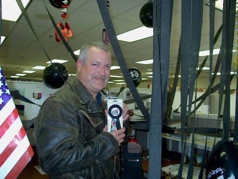 1998 Ford Crown Victoria - Man holding a ribbon award in an office setting with decorations.