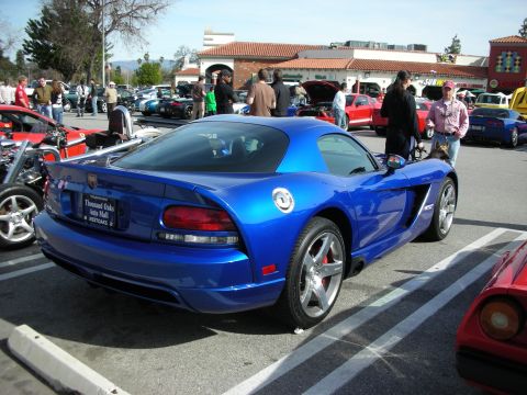 1998 Ford Crown Victoria - blue Dodge Viper coupe seen from the rear three-quarter in a busy parking-lot car show, with a dealer plate frame.