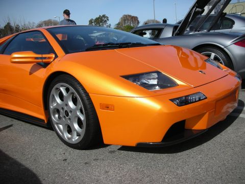 1998 Ford Crown Victoria - orange Lamborghini Diablo shown front three-quarter with multi-spoke wheels, parked at an outdoor car show.