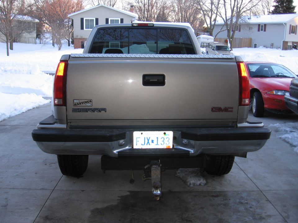 1998 GMC Sierra 1500 pickup truck rear view, tan color, with a trailer hitch and license plate FJX-133