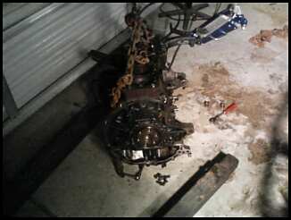 1995 Ford Probe - An engine assembly is suspended by a chain hoist in a garage setting, with tools scattered on the floor.