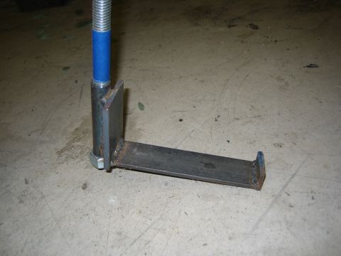 1996 Ford Bronco - A shop-fabricated steel bracket sitting on a concrete floor, made from a flat bar welded at right angles to an upright plate and a nut, wit…