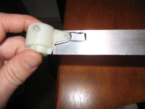1990 Ford Bronco - A white plastic component is held against a metal strip, showing a cutout section.