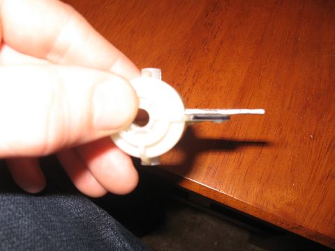 1990 Ford Bronco - A white plastic component with a thin metal lever is held in a hand against a wooden surface.