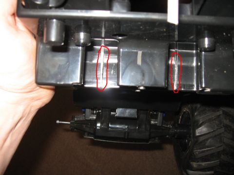 1990 Ford Bronco - Close-up view of the underside of a toy truck chassis, with specific plastic parts highlighted by red circles.