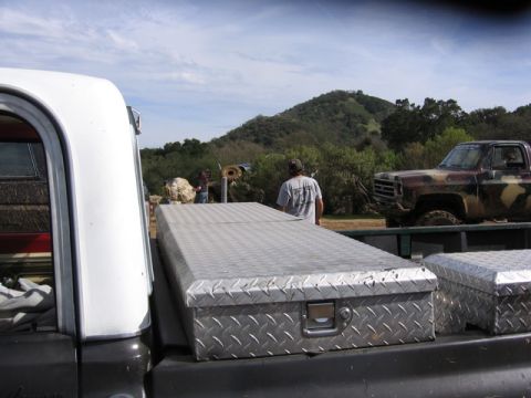 1989 Ford Bronco - A camouflaged pickup truck with off-road tires is parked in a rural setting.