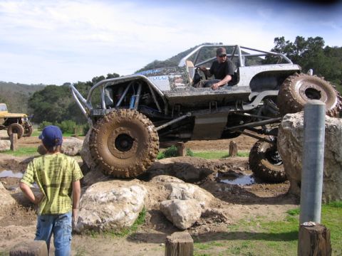 1989 Ford Bronco - Custom buggy tackles a challenging off-road course with a spectator watching.
