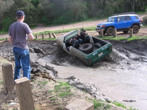 1989 Ford Bronco - Two off-road vehicles are stuck in thick mud, with one vehicle's tailgate clearly marked.