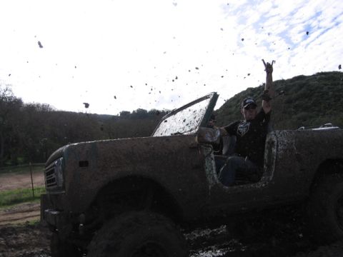 1989 Ford Bronco - A driver celebrates while navigating a muddy trail in an off-road vehicle.