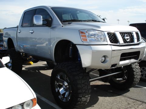 1994 Ford Bronco - This lifted Nissan Titan pickup truck features large off-road tires and chrome wheels, suggesting significant suspension modifications.