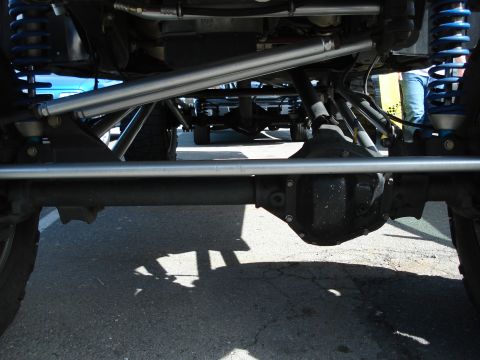 1994 Ford Bronco - Close-up of the undercarriage and suspension of a heavily modified off-road vehicle.