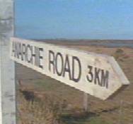 1998 Ford Crown Victoria - A weathered wooden signpost indicates the direction and distance to Anarchie Road.