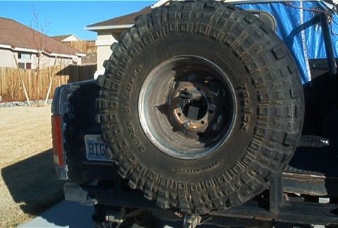 1986 Ford Bronco - The rear of a 1986 Ford Bronco is visible, a large, externally mounted spare tire and a "BIG" license plate.