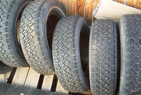 1986 Ford Bronco - A collection of tires, some with visible studs, are displayed against a wooden background.