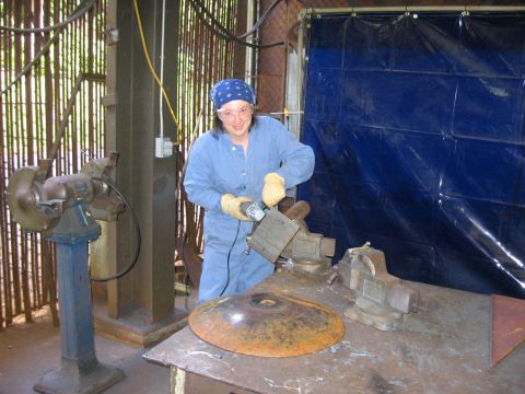 1976 Ford F-150 - Workshop scene with a person grinding metal, with a bench grinder and other tools visible.