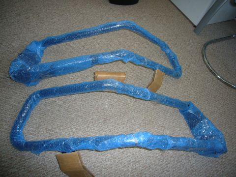 2000 Ford Crown Victoria - Two automotive parts, likely for a vehicle, are packaged for protection on a carpeted surface.