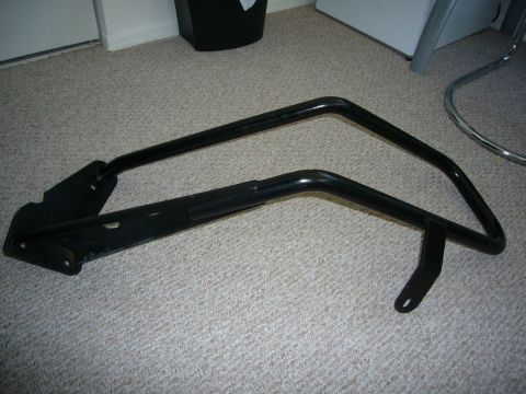 2000 Ford Crown Victoria - This black metal part, possibly a guard or frame, is shown on a carpeted floor. Its specific vehicle application is not identifiable from t…