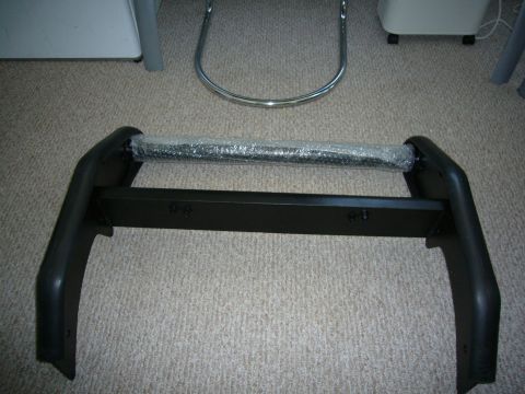 2000 Ford Crown Victoria - This black bull bar, wrapped in bubble wrap on its horizontal bar, is presented as a vehicle part.