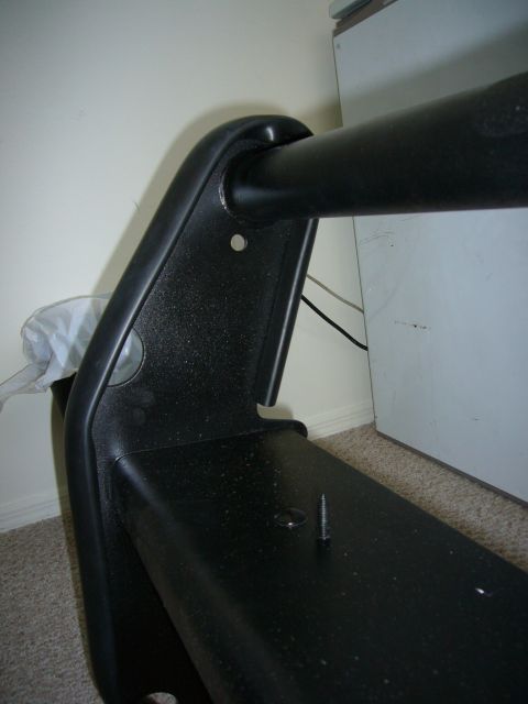 2000 Ford Crown Victoria - Close-up of a black plastic vehicle bumper part and a metal bar.