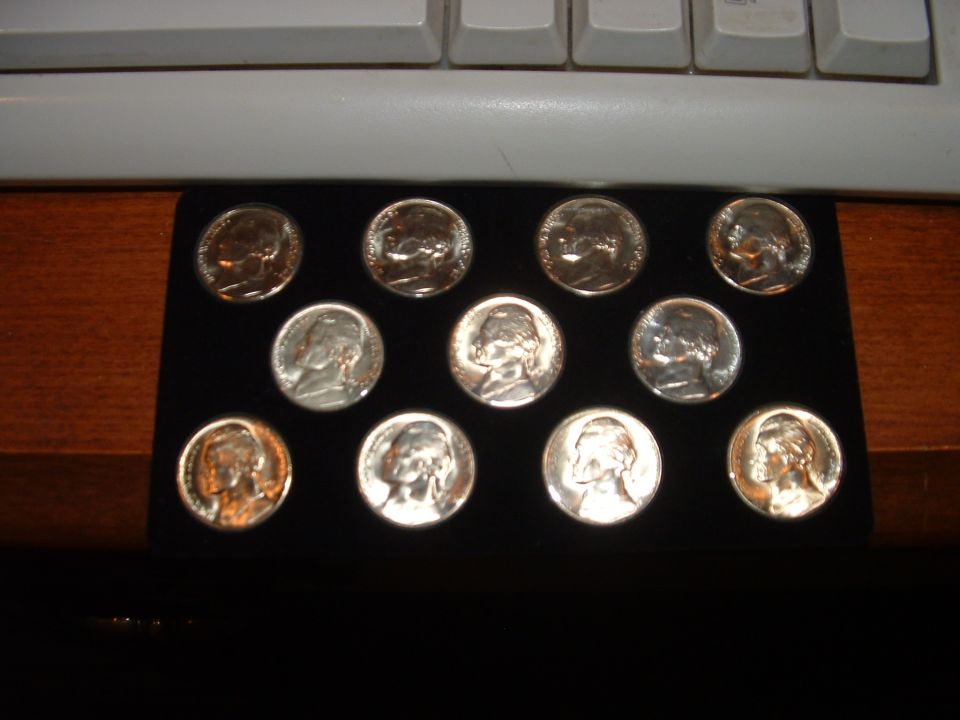 Eleven uncirculated coins arranged on a black tray