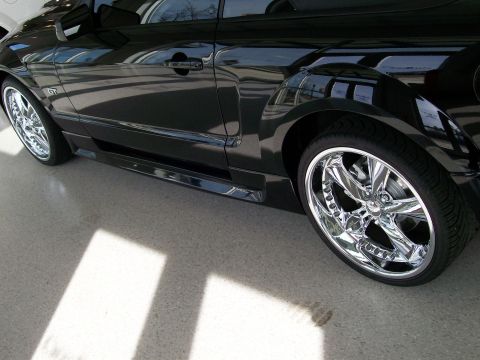 1996 Ford Bronco - The side profile of a black car is shown with large chrome rims and custom bodywork.