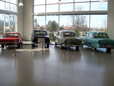 1996 Ford Bronco - A collection of classic automobiles are displayed indoors, viewed from behind.