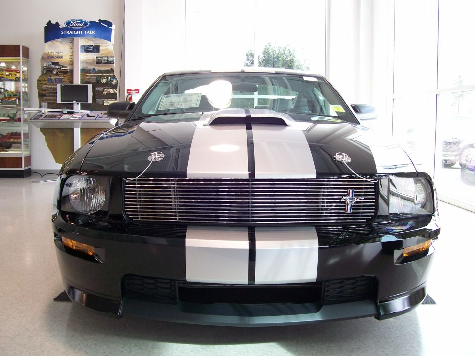 Black Ford Mustang with silver racing stripes, front view