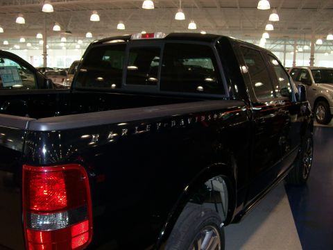 1996 Ford Bronco - A black pickup truck with Harley-Davidson badging is parked indoors next to another vehicle.